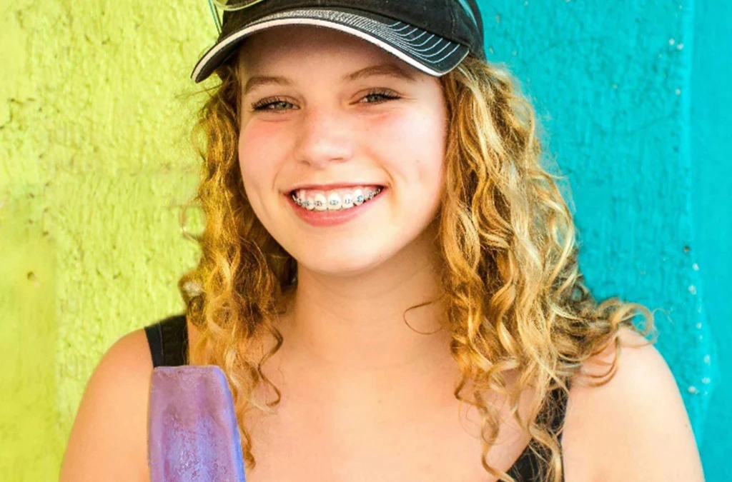 smiling girl with braces enjoying a popsicle